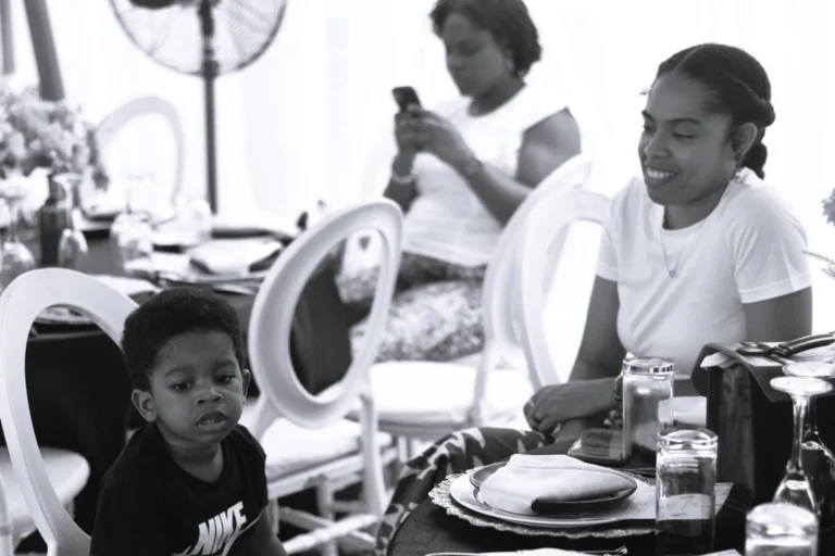 Black-and-white shot of mother and child seated at a marquee table with guests.