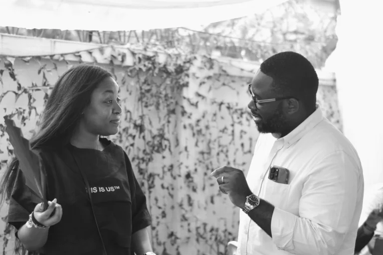 Woman and bearded man in white shirt converse in a monochrome outdoor portrait.