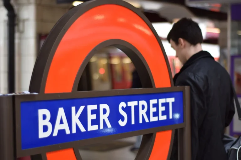 Iconic red and blue London Underground roundel for Baker Street station with a commuter walking past.