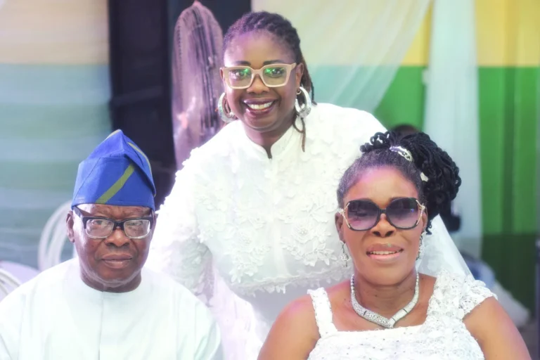 Older couple and a younger woman in glasses pose together at a celebration.