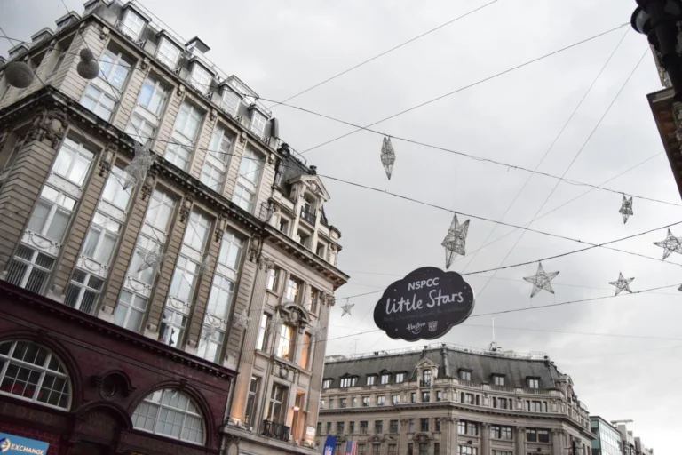 Oxford Circus festive star lights and NSPCC Little Stars banner strung above Regent Street buildings.