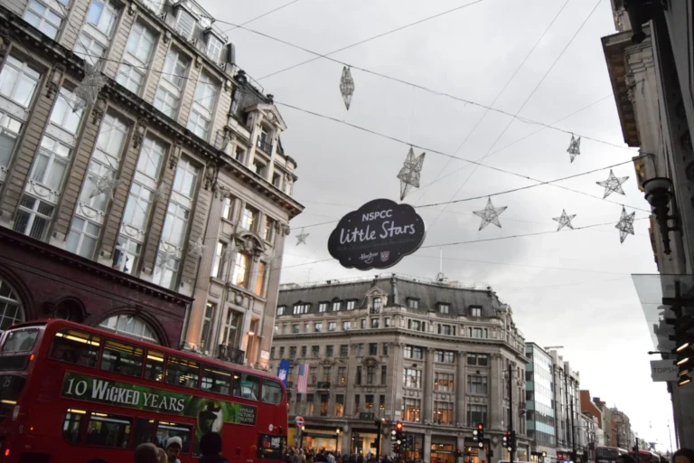 Red London bus with '10 Wicked Years' advert passes beneath NSPCC Little Stars Christmas decorations.