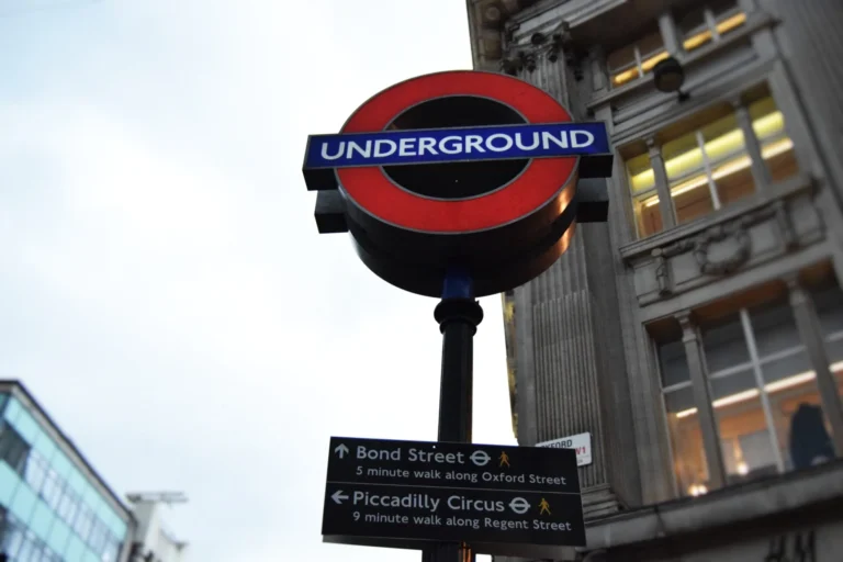 Illuminated London Underground roundel with directional signs pointing to Bond Street and Piccadilly Circus.
