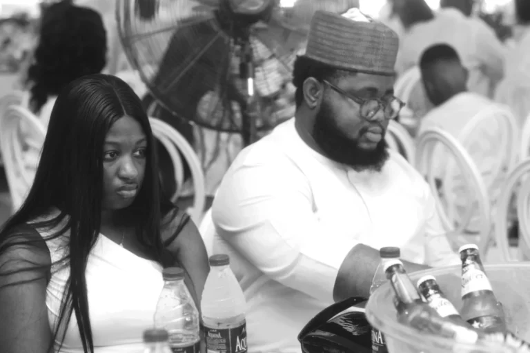 Young couple sit at a banquet table behind ice buckets in black and white.