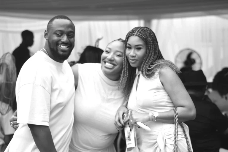 Black-and-white photo of three friends smiling closely together for a portrait.