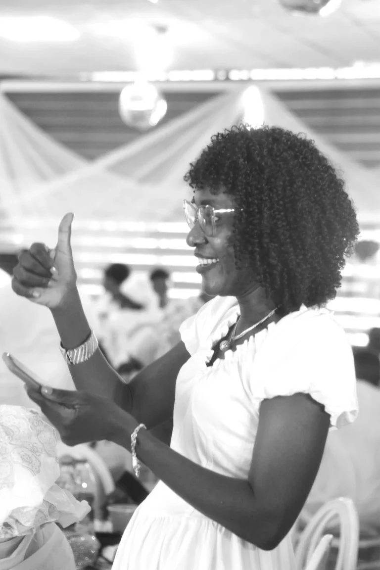 Young woman in glasses gives a thumbs up while dancing under disco lights.