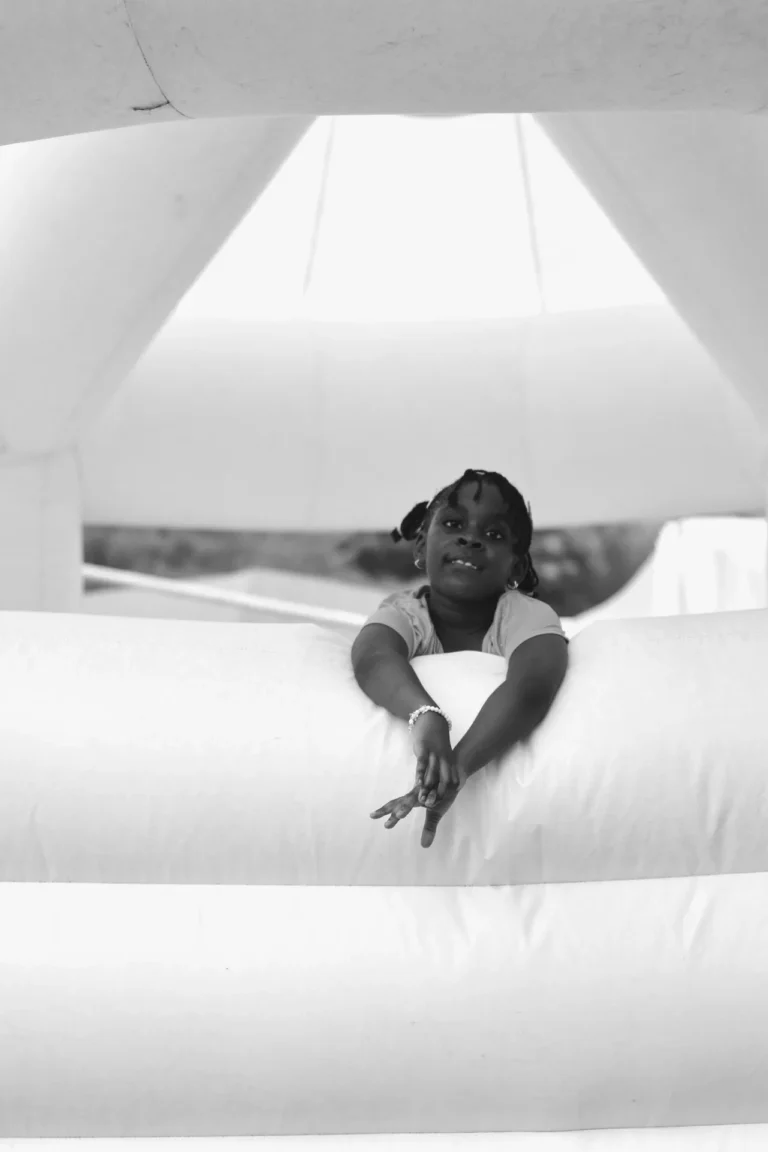 Black-and-white image of a girl leaning over the side of an inflatable bouncy castle.