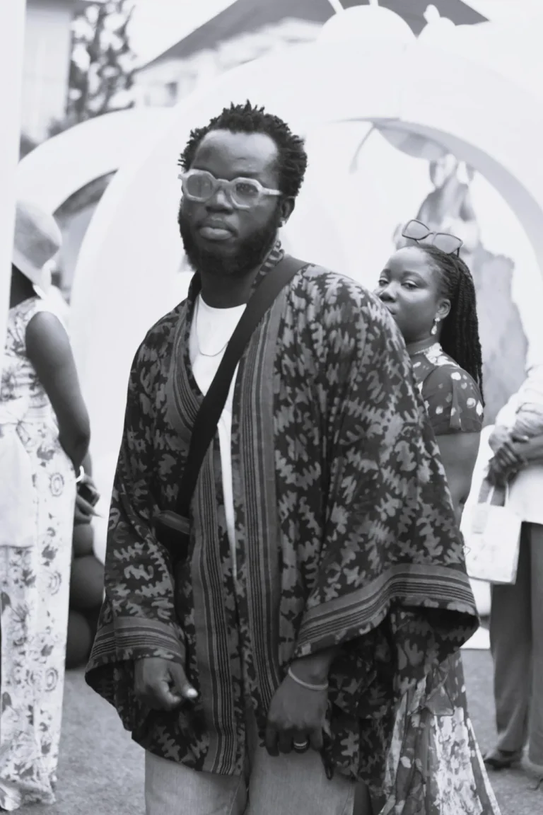 Black-and-white portrait of a bearded man in clear glasses and a patterned kimono-style robe.