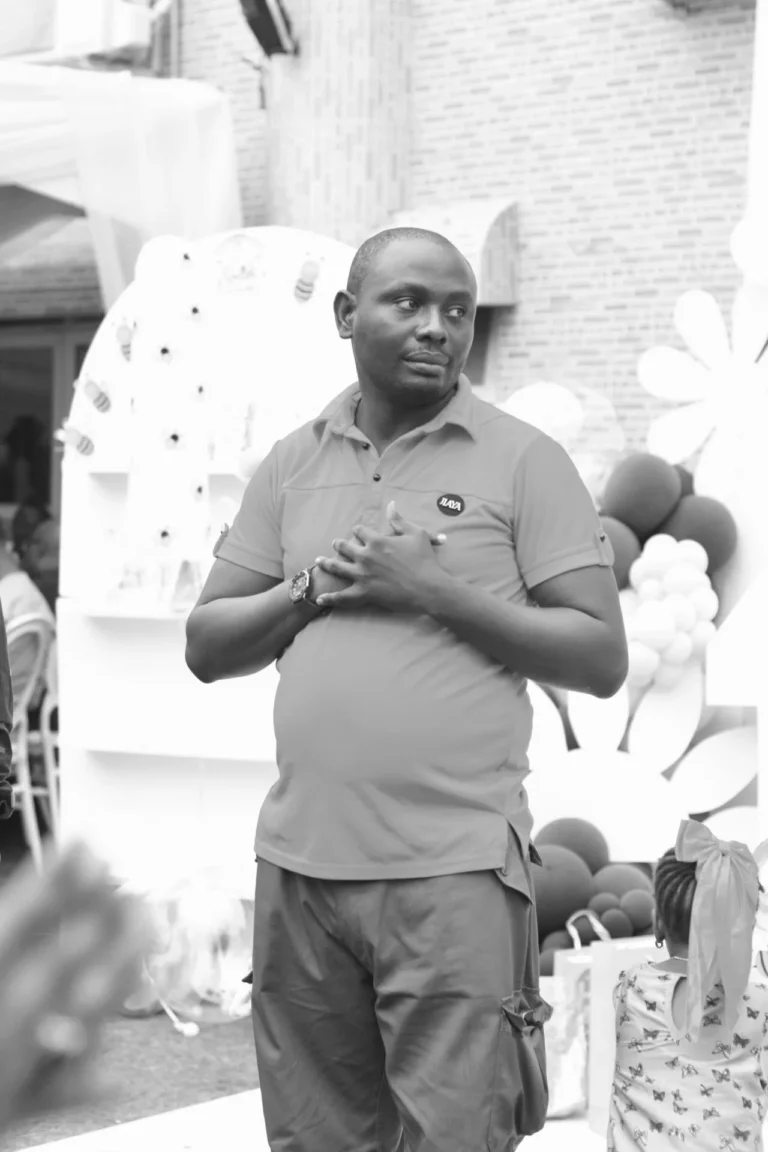 Black-and-white photo of a man in a polo shirt with hands clasped on his chest.